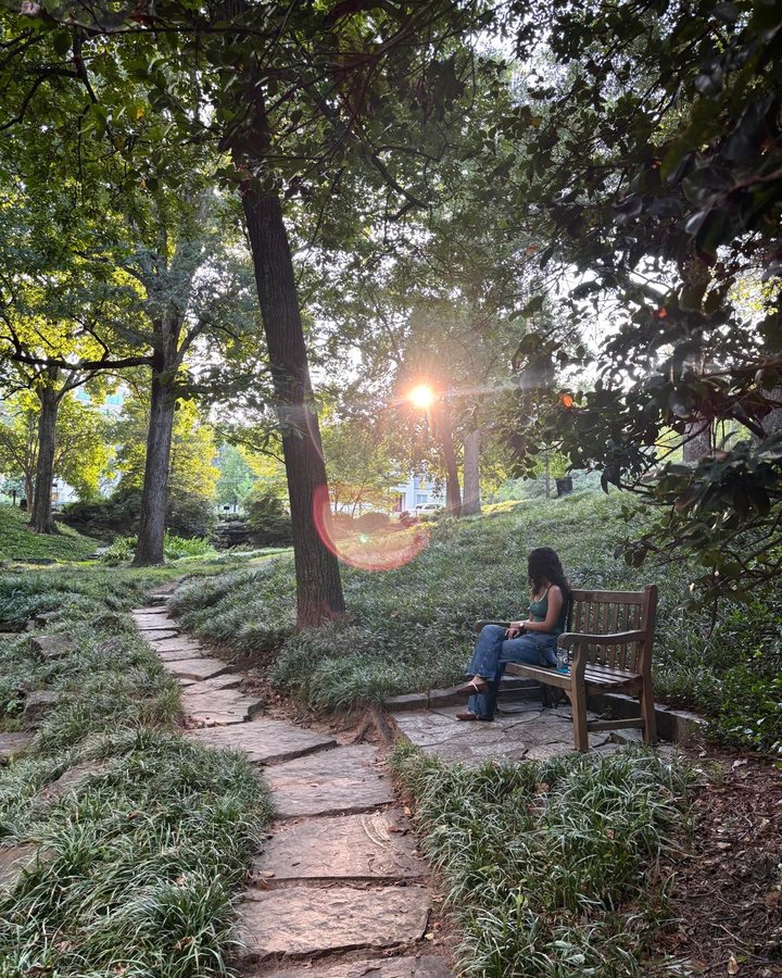 Simar on a park bench under the trees at golden hour