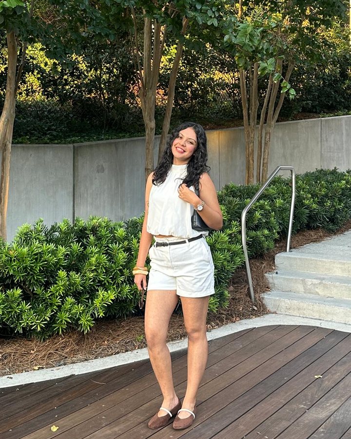 Simar in a white top and shorts, smiling outdoors